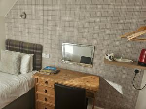 a bedroom with a bed and a desk with a mirror at Dunskaith Villa in Inverness