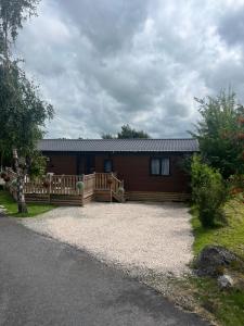 une cabane en rondins avec une véranda et une terrasse dans l'établissement Bolton Beer Escape Lodge, à Warton