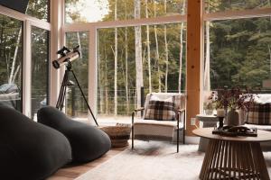 a room with a camera and a tripod in front of windows at Starry Tremblant l Design Glass View Cabin Spa Lake in Saint-Rémi-dʼAmherst