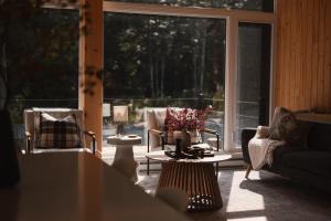 - un salon avec une table, des chaises et une grande fenêtre dans l'établissement Starry Tremblant l Design Glass View Cabin Spa Lake, à Saint-Rémi-dʼAmherst