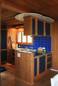 a kitchen with wooden cabinets and a blue tile wall at Haus am Seeufer mit Veranda in natürlicher Umgebung in Güttingen