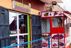 VINTEX GUEST HOUSE في Kimana: متجر بأبواب ونوافذ حمراء وأخضر