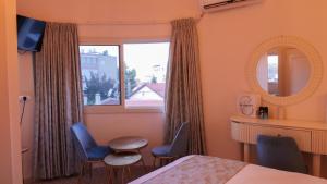 um quarto com uma cama e duas cadeiras e um espelho em German Colony Apartments em Haifa