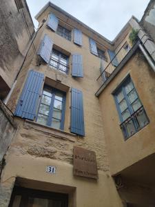 un bâtiment avec des fenêtres bleues à volets dans l'établissement Les suites de charme du Portalet, à Uzès