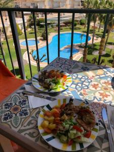 einen Tisch mit 2 Tellern Essen auf einem Balkon in der Unterkunft Beachfront Merced apartman in El Campello