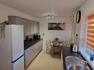 uma cozinha com um frigorífico branco e uma mesa em Dulverton house - 3 bed house /sleeps 6+ driveway+close to M1 em Nottingham