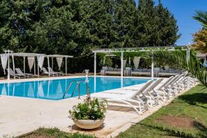 a pool with chaise lounge chairs and a pavilion at Masseria Montepaolo Dimora di Charme in Conversano