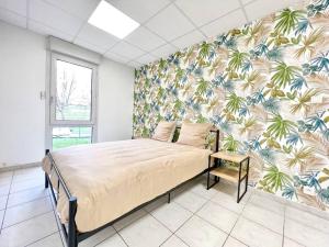 um quarto com uma cama com papel de parede tropical em Le Grand Penon ~ Logement Spacieux à 6 min du Parc em Saint-Georges-lès-Baillargeaux