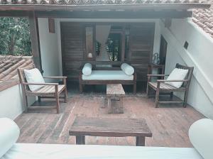 un patio con 2 sillas, un sofá y una mesa en Monkey Casa Hotel en Trancoso