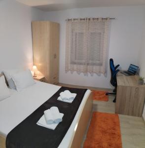 een slaapkamer met een bed en een bureau met een laptop bij Apartments Valentino in Gradac