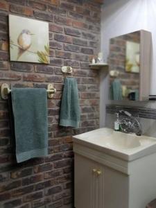 a bathroom with a sink and a brick wall at Hedgehog Cabin in Marloth Park