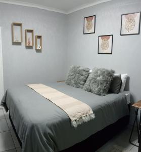 a white bedroom with a bed with grey pillows at Be Our Guest Near OR TAMBO International Airport in Boksburg