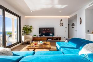 sala de estar con sofás azules y TV en Luxury penthouse with huge terrace and sea and golf views, en San Roque