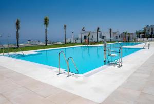 a swimming pool with blue water and palm trees at Luxury penthouse with huge terrace and sea and golf views in San Roque