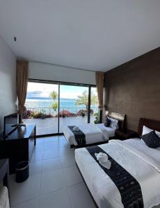 a hotel room with two beds and a large window at Tiara Bunga Hotel & Villa in Balige