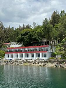 a large white building next to a body of water at Tiara Bunga Hotel & Villa in Balige