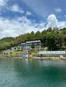 a building on a hill next to a body of water at Tiara Bunga Hotel & Villa in Balige