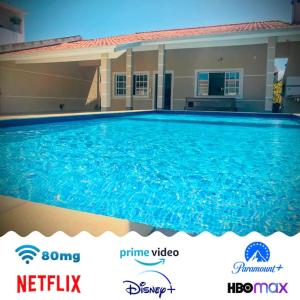 uma grande piscina azul em frente a uma casa em Casa de praia com piscina e churrasqueira - Indaiá Bertioga em Bertioga