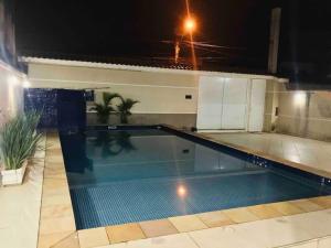 - une piscine dans une maison la nuit dans l'établissement Casa de praia com piscina e churrasqueira - Indaiá Bertioga, à Bertioga
