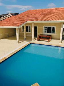 uma casa com piscina em frente a uma casa em Casa de praia com piscina e churrasqueira - Indaiá Bertioga em Bertioga