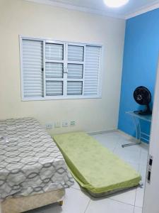 - une chambre avec un lit et une fenêtre avec un ventilateur dans l'établissement Casa de praia com piscina e churrasqueira - Indaiá Bertioga, à Bertioga