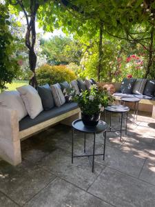 un sofá sentado en un patio con 2 mesas en Mas Serena, en Ménerbes