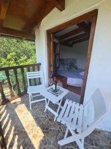 un patio con 2 sillas, una mesa y una cama en Refugio Finca El Canu en Valdaliga 