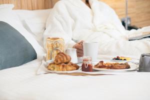a person sitting on a bed with two plates of food at Fistral Beach Hotel and Spa - Adults Only in Newquay