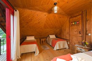 a room with two beds in a wooden cabin at Pousada Fazenda Rio das Pedras in Visconde De Maua