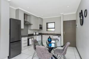 a kitchen with a glass table and two chairs at Captivating 2-Bed Apartment in Sandton in Sandton