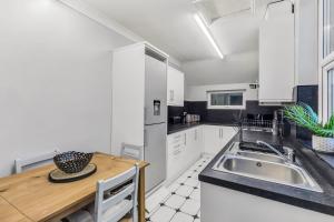 a kitchen with white cabinets and a wooden table at Ashby House in Coalville