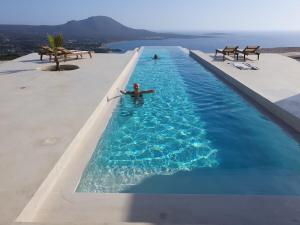 a man laying in a swimming pool on a beach at Mr. Bliss in Avlemonas