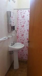baño con lavabo y cortina de ducha con rosas en Departamentos Posada de los angeles en Capilla del Monte