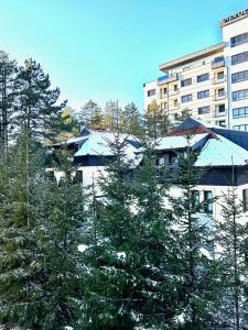a building with snow covered trees in front of a building at Apartman Dharma Zlatibor in Zlatibor