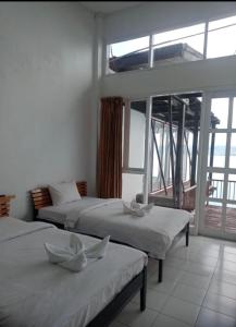 a bedroom with two beds and a large window at Tiara Bunga Hotel & Villa in Balige