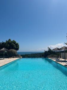 una piscina con agua azul y sombrillas en Camping Rondinara, en Bonifacio