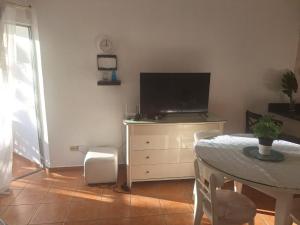 ein Wohnzimmer mit einem Tisch und einem TV auf einer Kommode in der Unterkunft Apartamento frente al mar Juan dolio in Juan Pedro