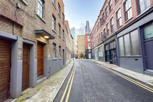 an empty street in an alley between brick buildings at Luxury Warehouse Conversion - Shoreditch in London