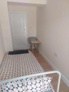 a small bedroom with a bed and a small table at Tollgate Drive in Southall