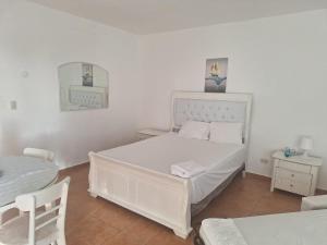 ein weißes Schlafzimmer mit einem weißen Bett und einem Tisch in der Unterkunft Apartamento frente al mar Juan dolio in Juan Pedro