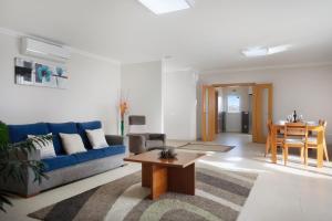 a living room with a blue couch and a table at Villa Rosa com Piscina e Jacuzzi in Salir de Matos +21 photos