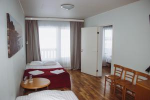 a hotel room with two beds and a table and chairs at Hotel Promenaadi in Haapsalu