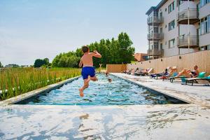 a young boy jumping into a swimming pool at West Bay Apartments in Middelkerke