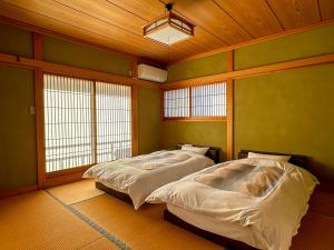 two beds in a room with green walls and windows at ハートリサイデェンス 河津 in Kawazu