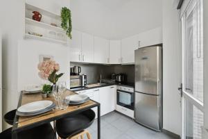 La cuisine est équipée de placards blancs et d'un réfrigérateur en acier inoxydable. dans l'établissement Chic apart terrace garden parking, à Asnières-sur-Seine