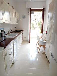 a kitchen with white cabinets and a white tile floor at La casa dei fiori in Florence