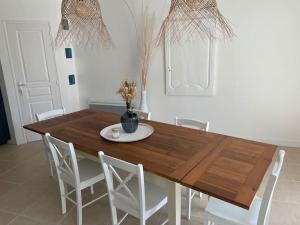 een eettafel met witte stoelen en een vaas erop bij Agréable maison de ville en bord de mer in Royan