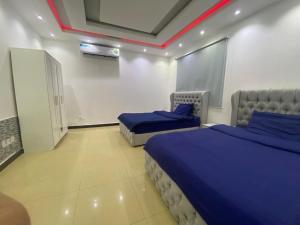 a bedroom with two beds with blue sheets at شاليه ثلاث غرف نوم في درة العروس in Durat  Alarous