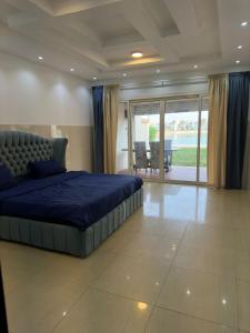 a bedroom with a large blue bed and a balcony at شاليه ثلاث غرف نوم في درة العروس in Durat  Alarous
