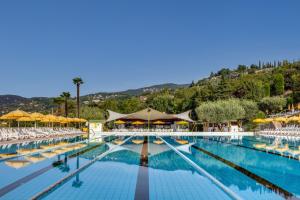 a large swimming pool with chairs and umbrellas at Poiano Garda Resort Appartamenti in Garda
